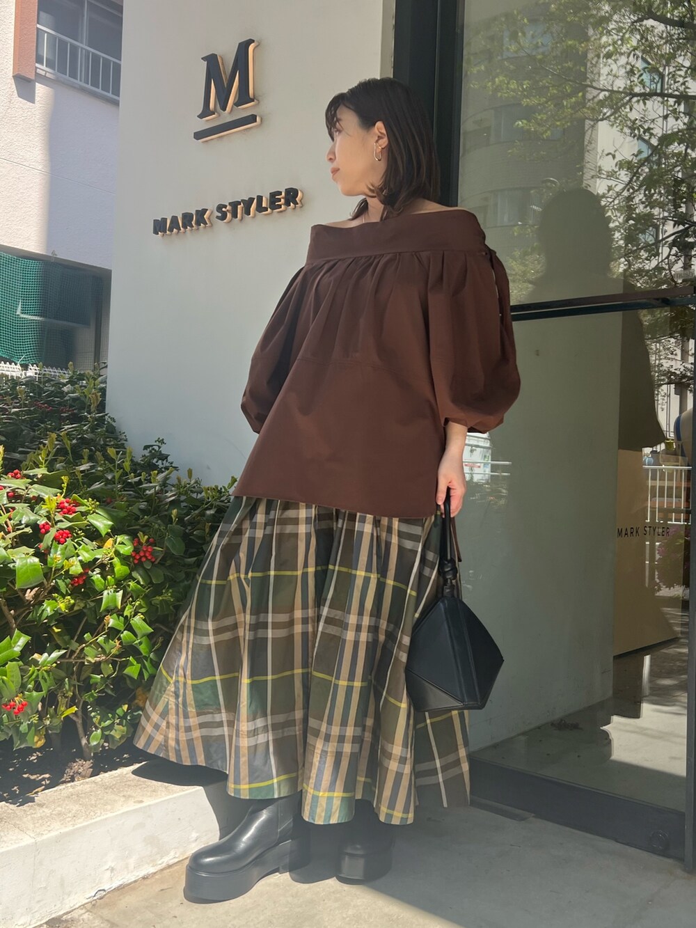 グリーン系のスカート、ブラウン系のシャツ/ブラウス、ブラック系のハンドバッグを着用したレディースの春コーディネートの6枚目の写真
