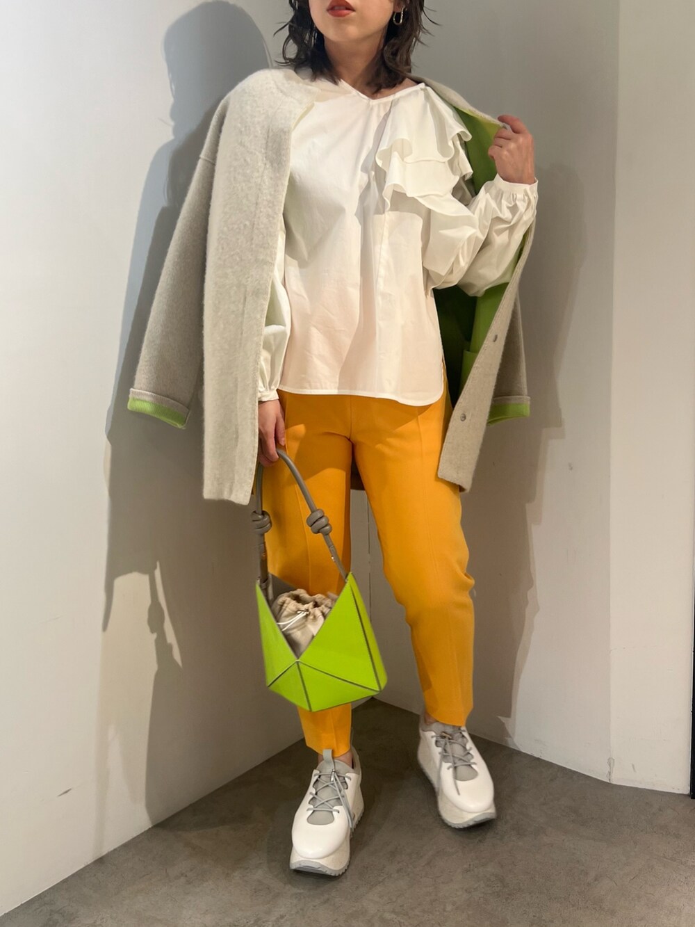 ホワイト系のシャツ/ブラウス、ホワイト系のカーディガン/ボレロ、イエロー系のハンドバッグを着用したレディースの冬コーディネートの2枚目の写真