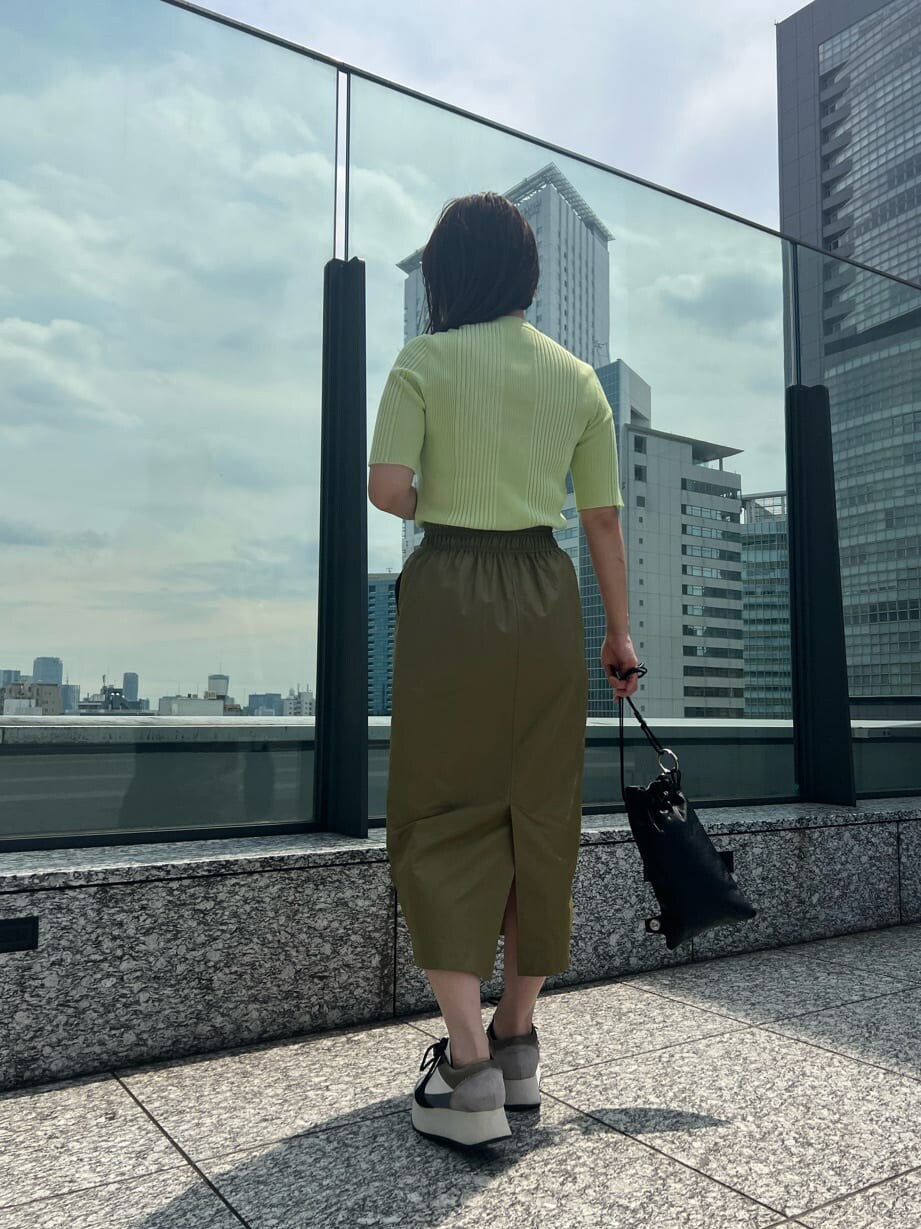 ベージュ系のスカート、ブルー系のスニーカー、グリーン系のニット/セーターを着用したレディースの夏コーディネートの6枚目の写真