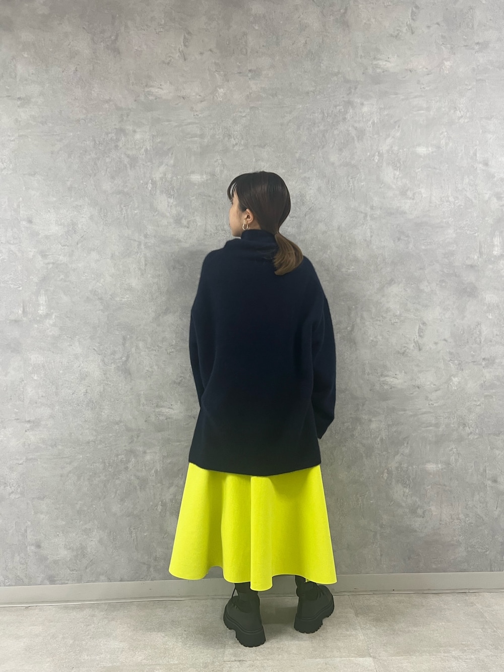 ブルー系のニット/セーター、ベージュ系のハンドバッグ、イエロー系のスカートを着用したレディースの秋コーディネートの3枚目の写真