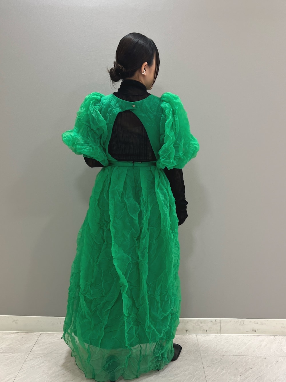 グリーン系のワンピース、ブラック系のニット/セーター、ブラック系のブーティを着用したレディースの夏コーディネートの4枚目の写真