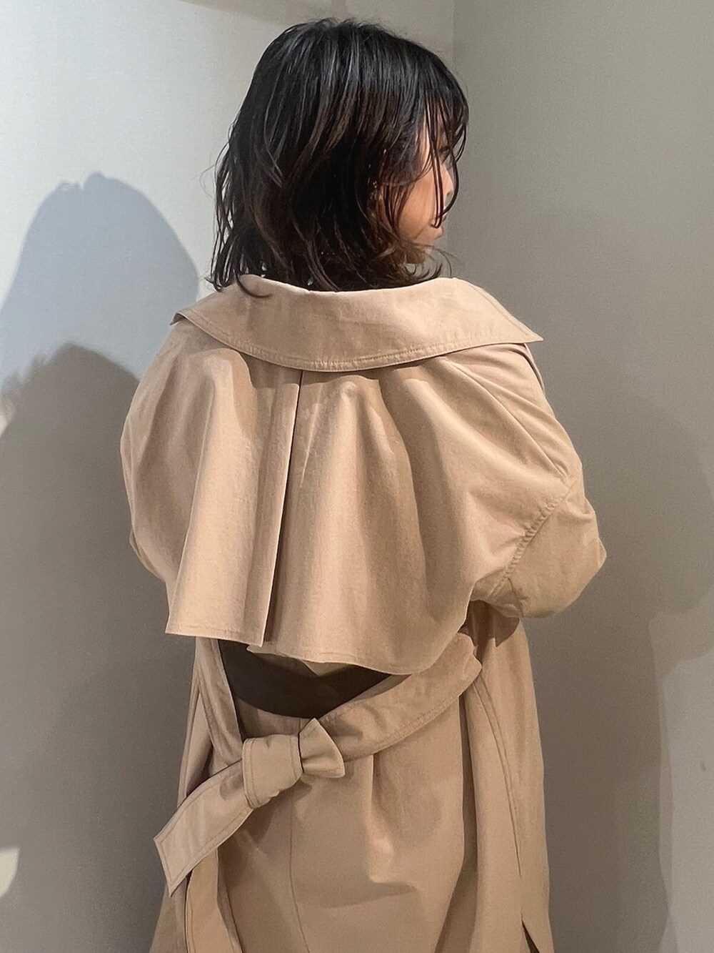 ベージュ系のトレンチコート、ブラック系のニット/セーター、ブルー系のデニムパンツを着用したレディースの冬コーディネートの5枚目の写真