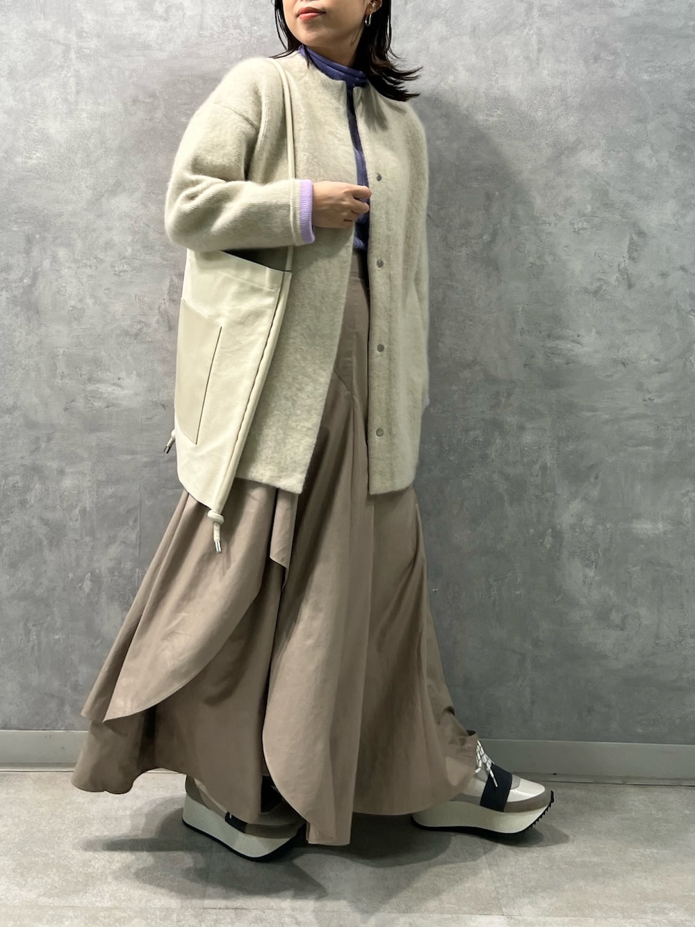 ホワイト系のノーカラージャケット、パープル系のニット/セーター、ベージュ系のスカートを着用したレディースの夏コーディネートの2枚目の写真