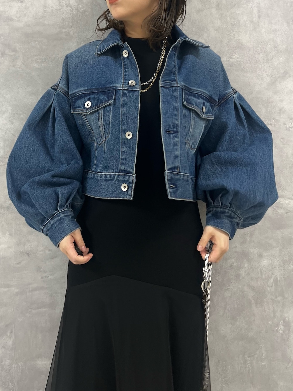 ブラック系のワンピース、ブルー系のデニムジャケット、ベージュ系のショルダーバッグを着用したレディースの冬コーディネートの3枚目の写真