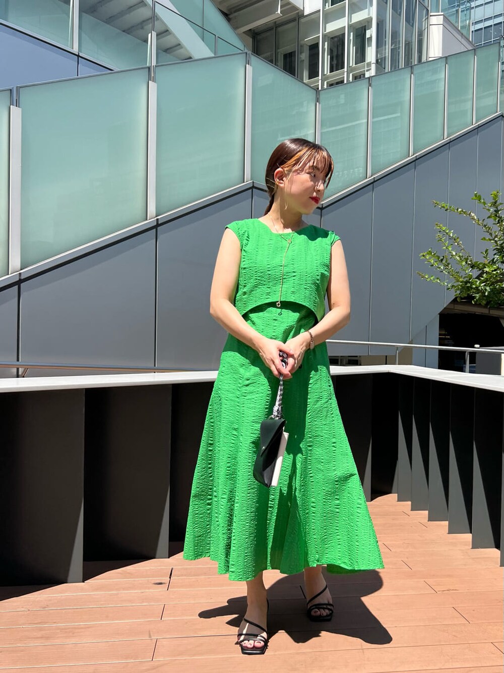 ブラック系のショルダーバッグ、グリーン系のワンピース、ブラック系のサンダルを着用したレディースの夏コーディネートの2枚目の写真