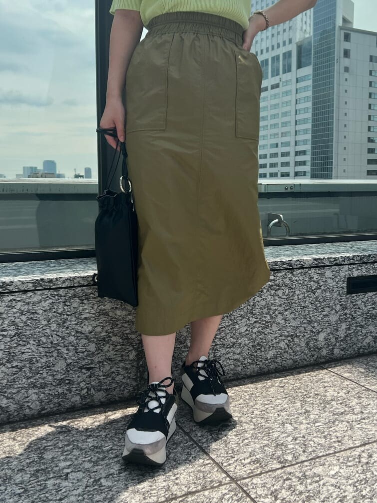 ベージュ系のスカート、ブルー系のスニーカー、グリーン系のニット/セーターを着用したレディースの夏コーディネートの4枚目の写真