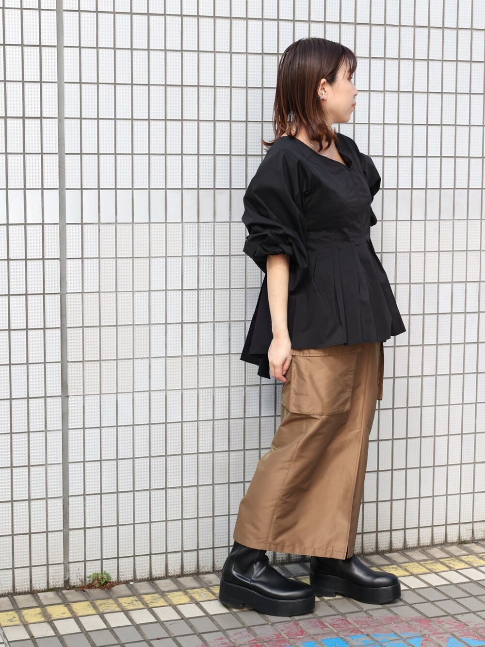 ブラウン系のスカート、ブラック系のシャツ/ブラウスを着用したレディースの春コーディネートの2枚目の写真