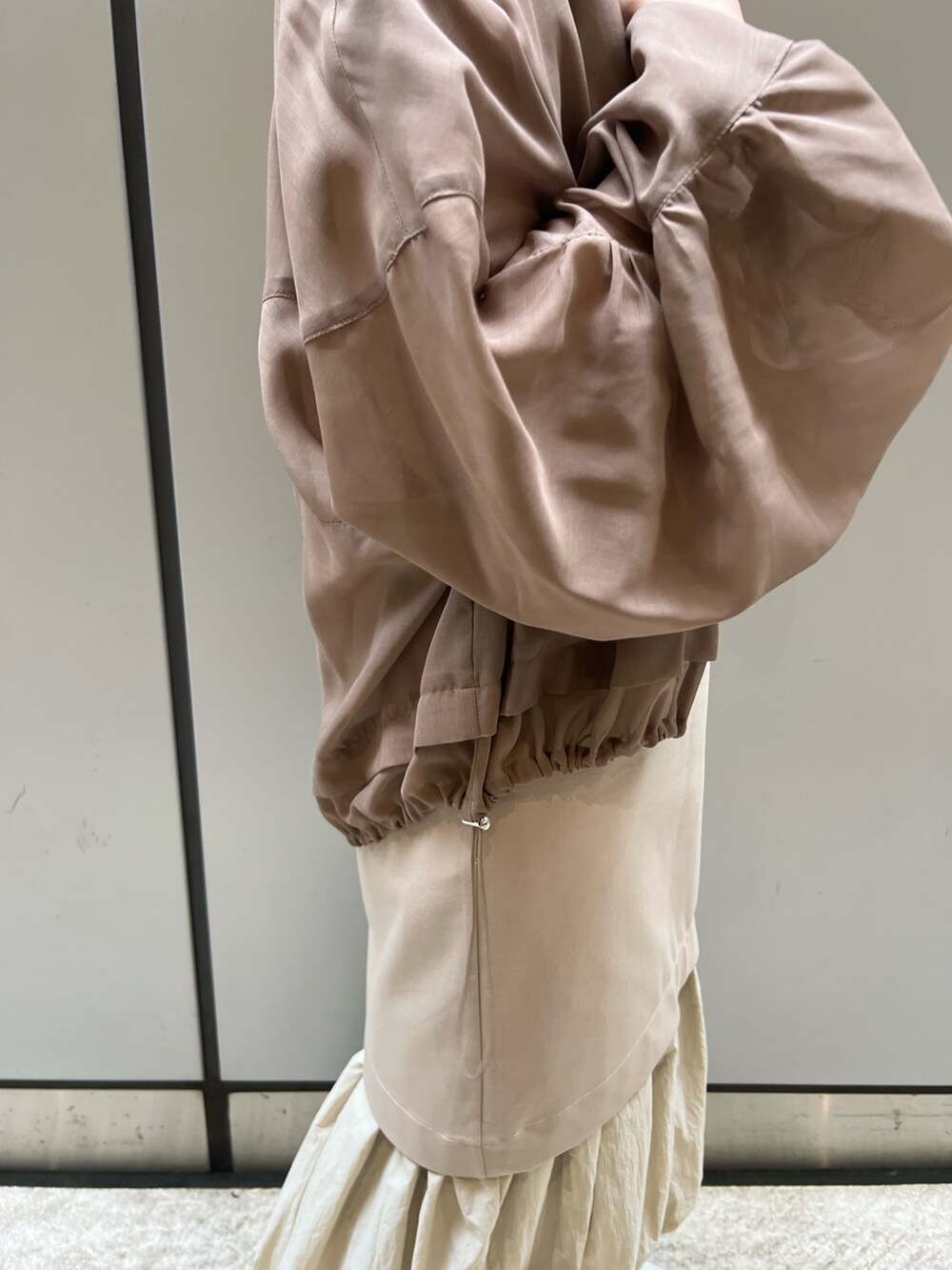 ベージュ系のワンピース、ホワイト系のスニーカー、ブラウン系のブルゾンを着用したレディースの春コーディネートの4枚目の写真