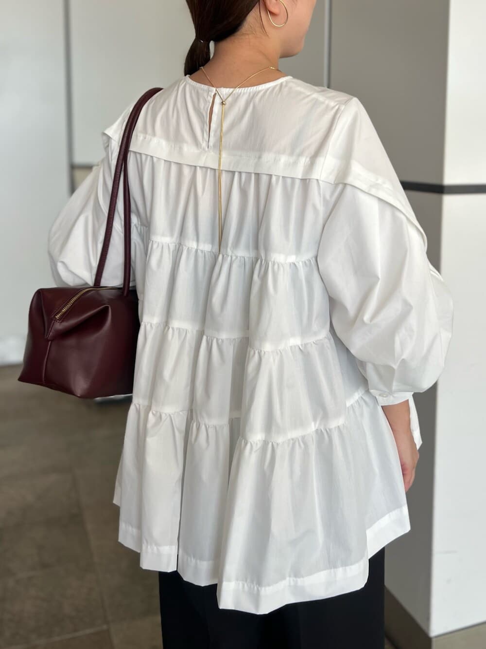 ホワイト系のシャツ/ブラウス、ブラック系のその他パンツ、レッド系のボストンバッグを着用したレディースの秋コーディネートの4枚目の写真