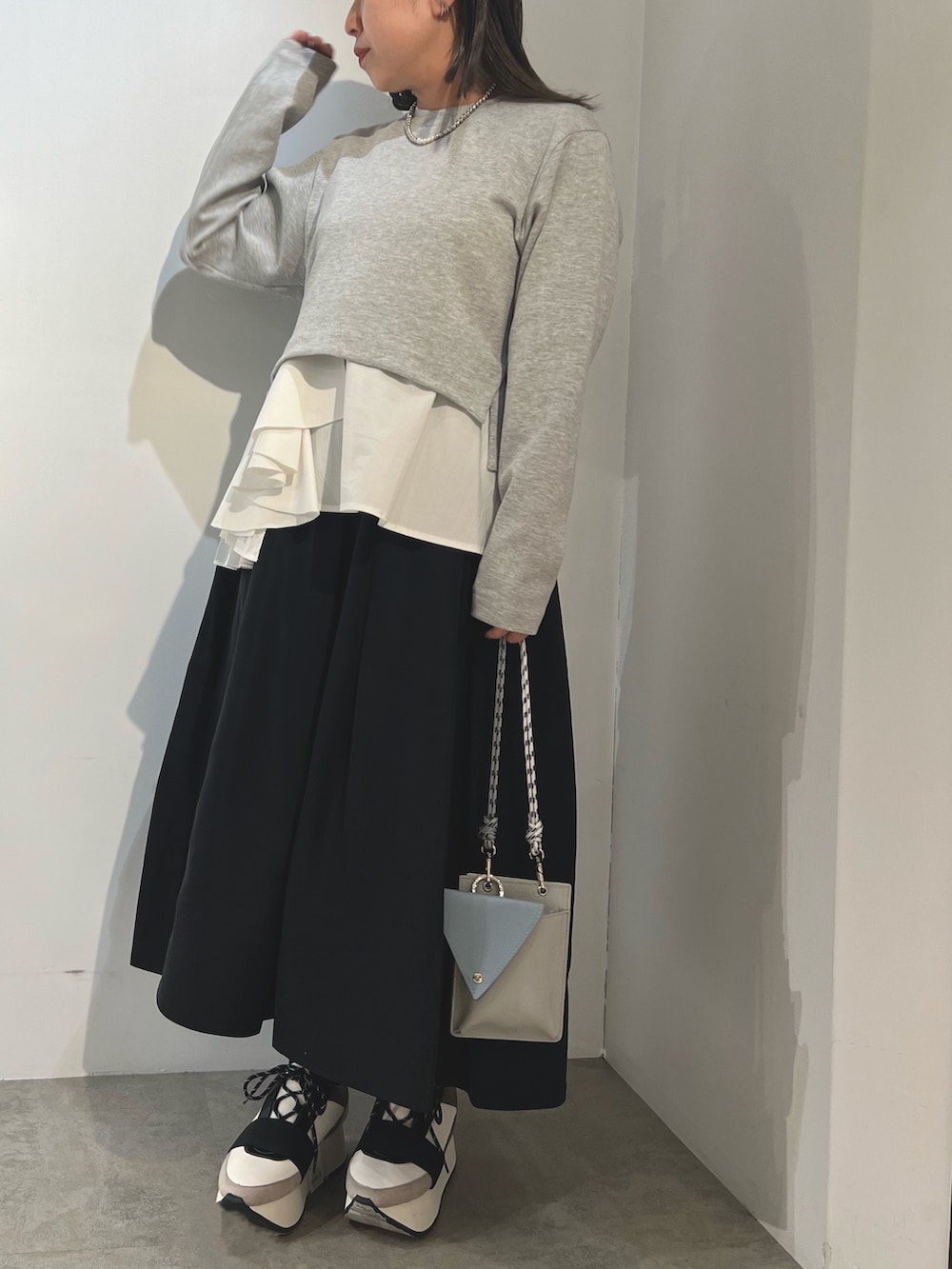 グレー系のTシャツ/カットソー、ブラック系のスカート、ブルー系のスニーカーを着用したレディースの冬コーディネートの3枚目の写真