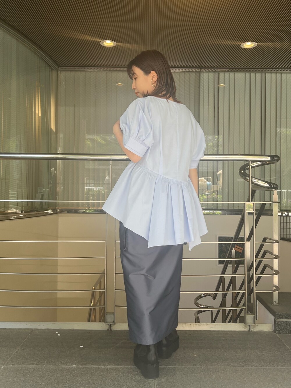 ブルー系のシャツ/ブラウス、ブルー系のスカート、ブラック系のブーツを着用したレディースの春コーディネートの3枚目の写真