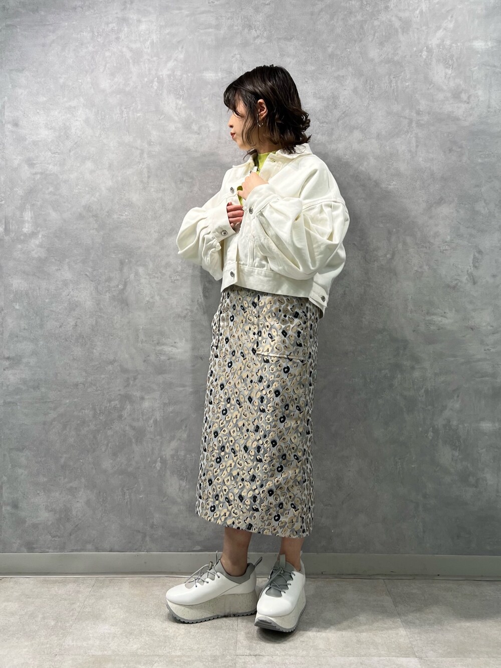 ホワイト系のデニムジャケット、グリーン系のニット/セーター、ベージュ系のスカートを着用したレディースの冬コーディネートの4枚目の写真