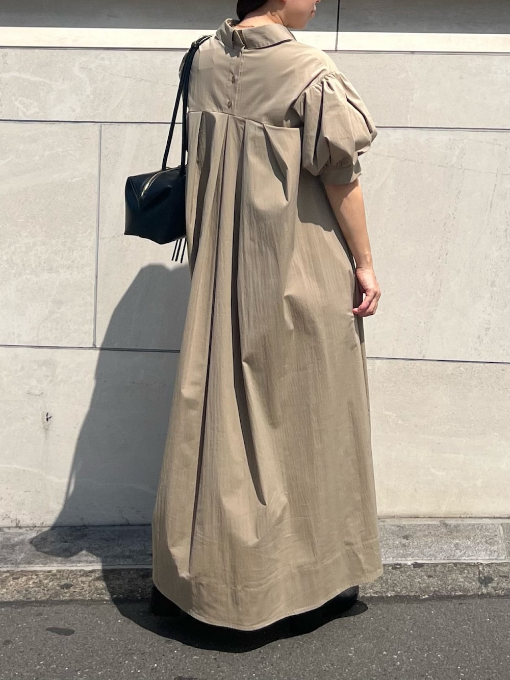 ベージュ系のワンピース、ブラック系のボストンバッグ、ブラック系のパンプスを着用したレディースの夏コーディネートの2枚目の写真