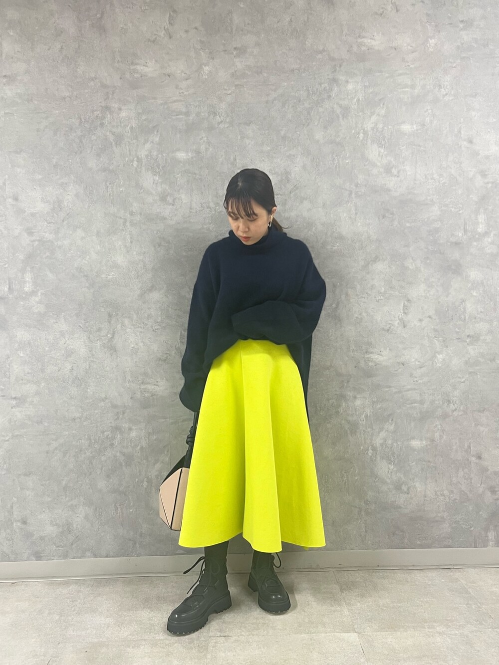 ブルー系のニット/セーター、ベージュ系のハンドバッグ、イエロー系のスカートを着用したレディースの秋コーディネートの2枚目の写真