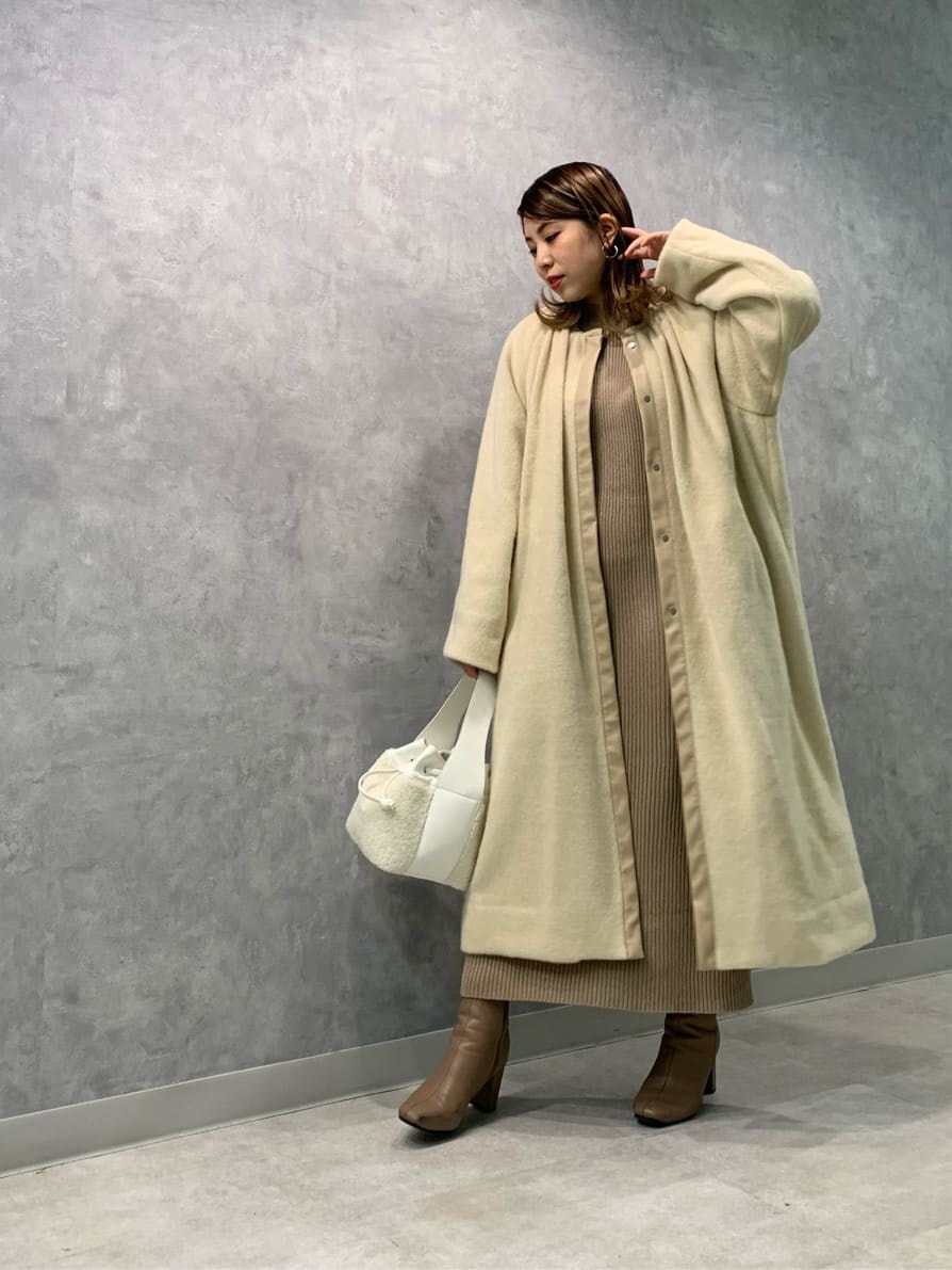ベージュ系のワンピース、ホワイト系のハンドバッグ、ベージュ系のノーカラーコートを着用したレディースの秋コーディネートの2枚目の写真