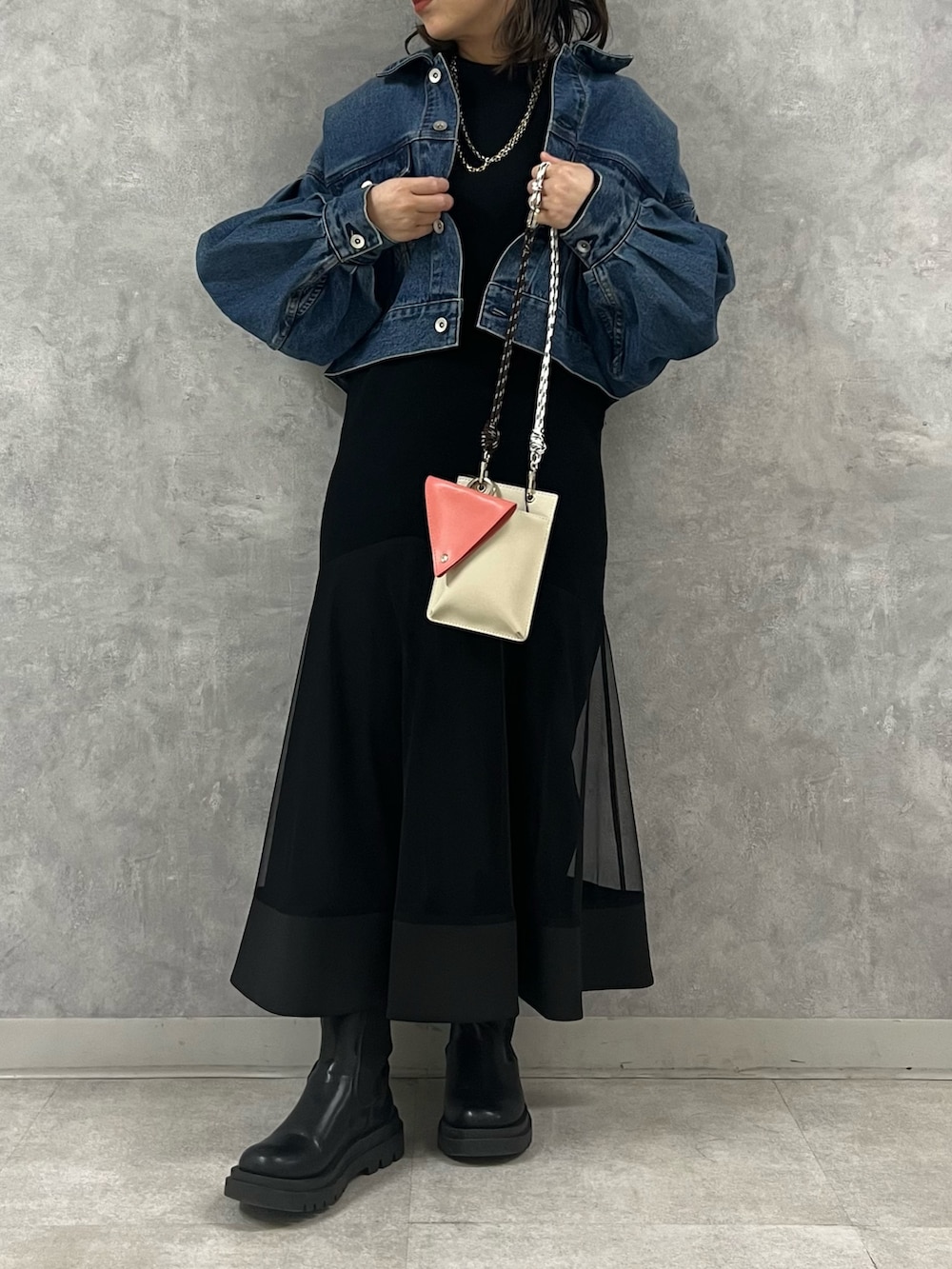 ブラック系のワンピース、ブルー系のデニムジャケット、ベージュ系のショルダーバッグを着用したレディースの冬コーディネートの2枚目の写真