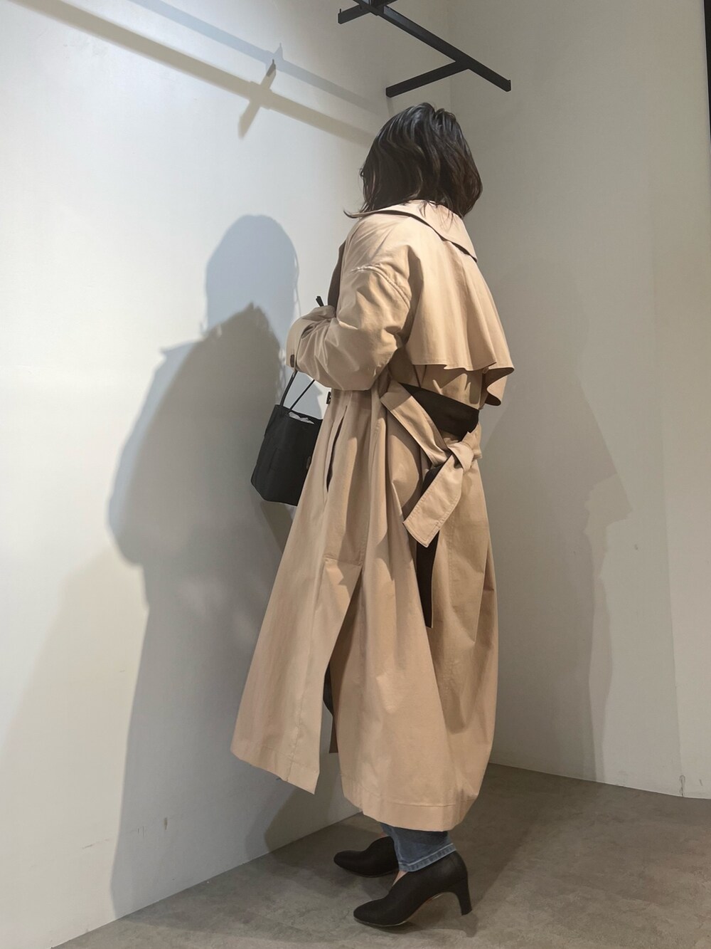 ベージュ系のトレンチコート、ブラック系のニット/セーター、ブルー系のデニムパンツを着用したレディースの冬コーディネートの6枚目の写真