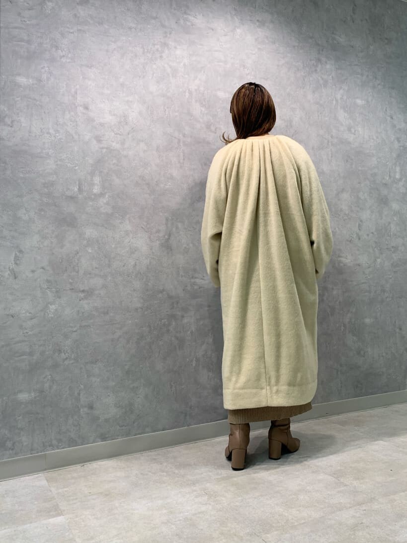 ベージュ系のワンピース、ホワイト系のハンドバッグ、ベージュ系のノーカラーコートを着用したレディースの秋コーディネートの5枚目の写真