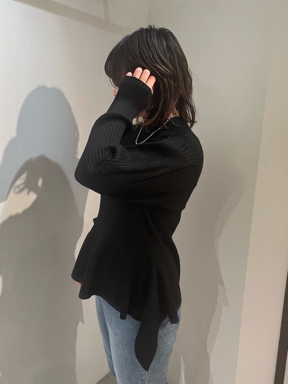 ベージュ系のトレンチコート、ブラック系のニット/セーター、ブルー系のデニムパンツを着用したレディースの冬コーディネートの8枚目の写真