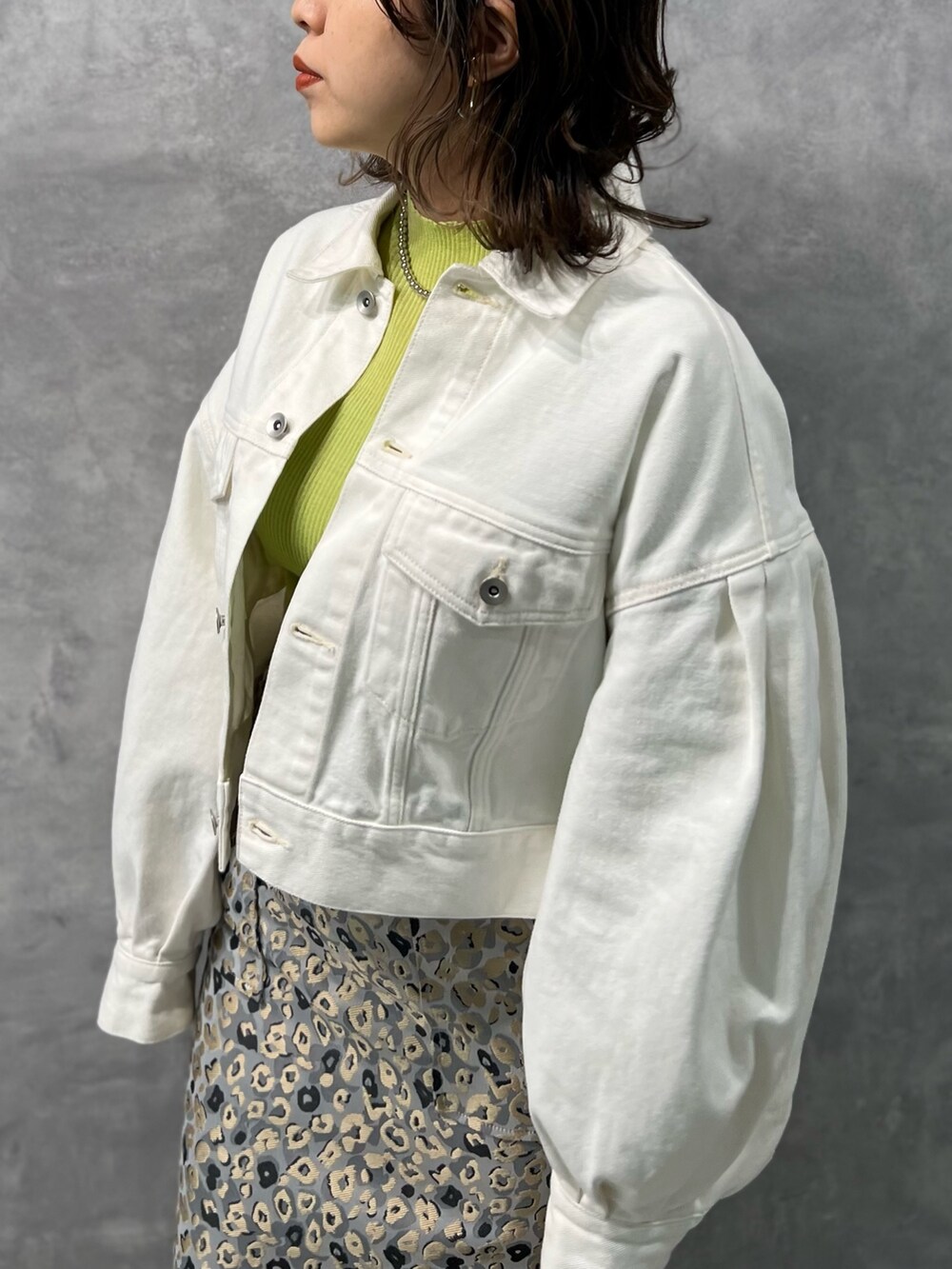 ホワイト系のデニムジャケット、グリーン系のニット/セーター、ベージュ系のスカートを着用したレディースの冬コーディネートの5枚目の写真