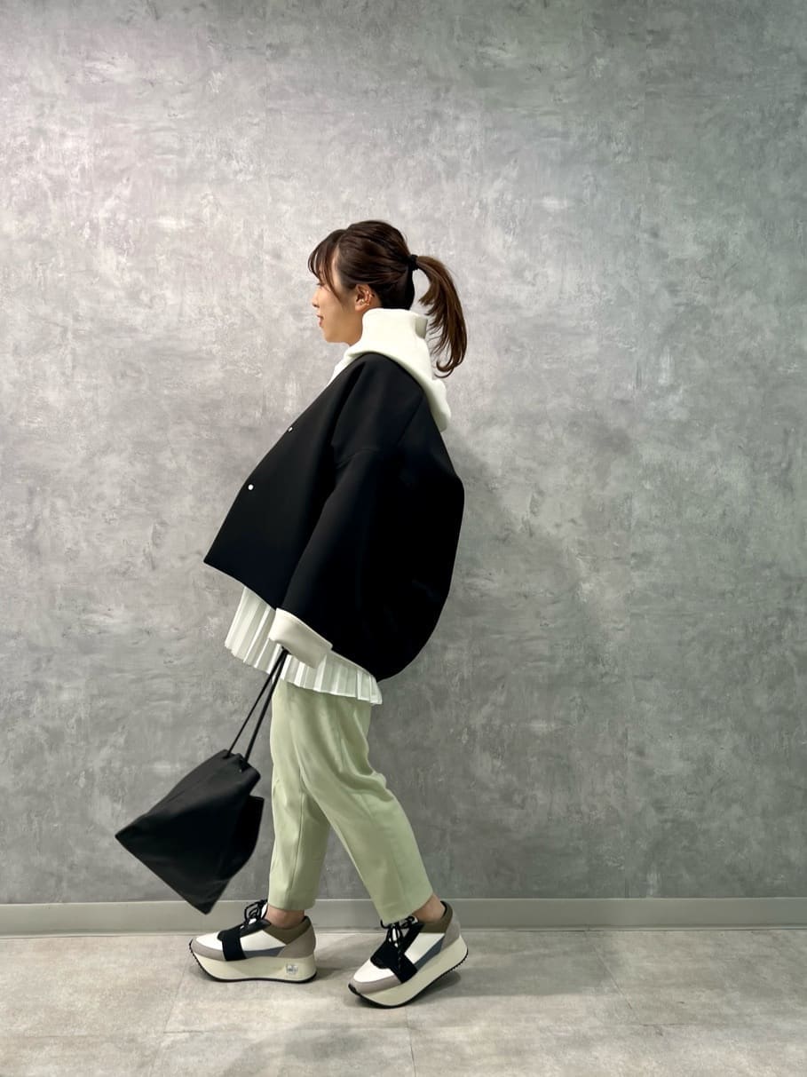 ブラック系のステンカラーコート、ピンク系のその他パンツ、ブルー系のスニーカーを着用したレディースの冬コーディネートの2枚目の写真