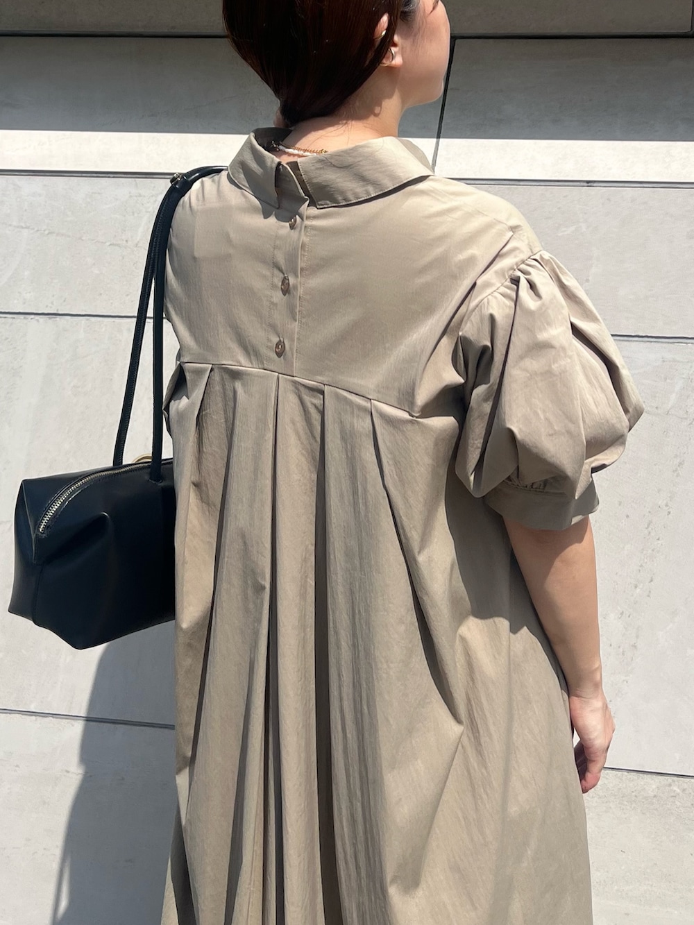 ベージュ系のワンピース、ブラック系のボストンバッグ、ブラック系のパンプスを着用したレディースの夏コーディネートの6枚目の写真