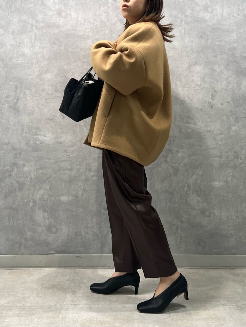 イエロー系のノーカラーコート、ブラウン系のその他パンツ、ホワイト系のニット/セーターを着用したレディースの秋コーディネートの4枚目の写真