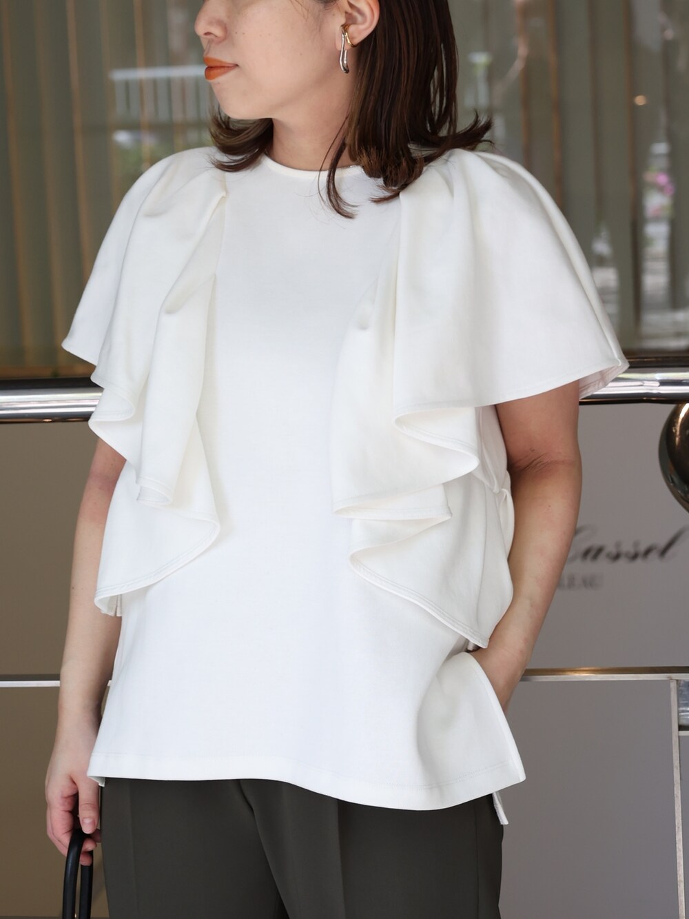 ホワイト系のTシャツ/カットソー、ブラック系のハンドバッグ、ブラック系のパンプスを着用したレディースの夏コーディネートの4枚目の写真