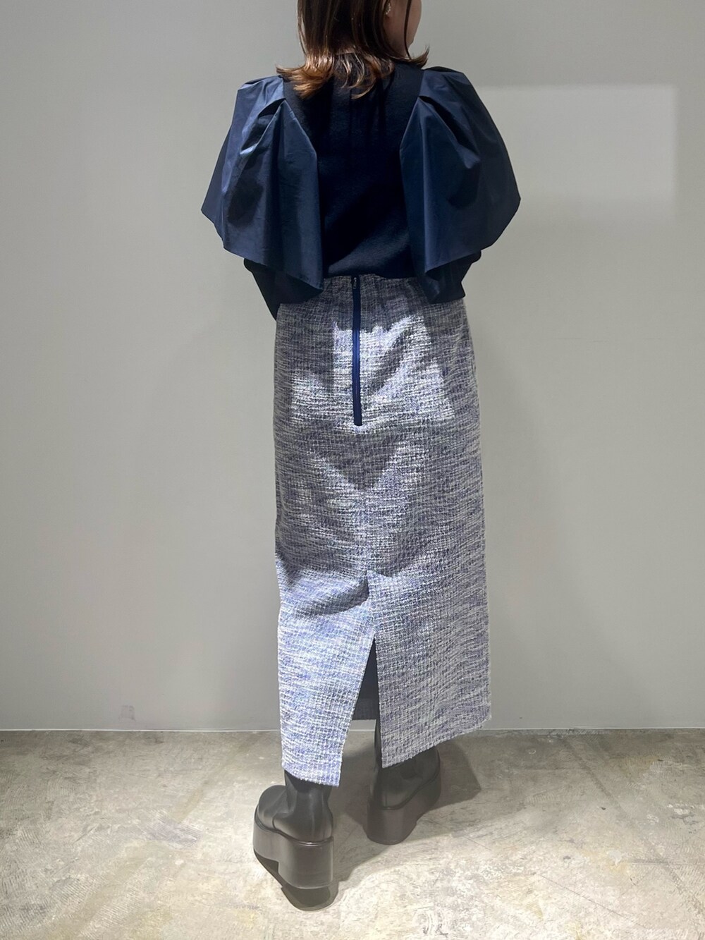 ブラック系のブーツ、ブルー系のニット/セーター、ブルー系のスカートを着用したレディースの春コーディネートの2枚目の写真