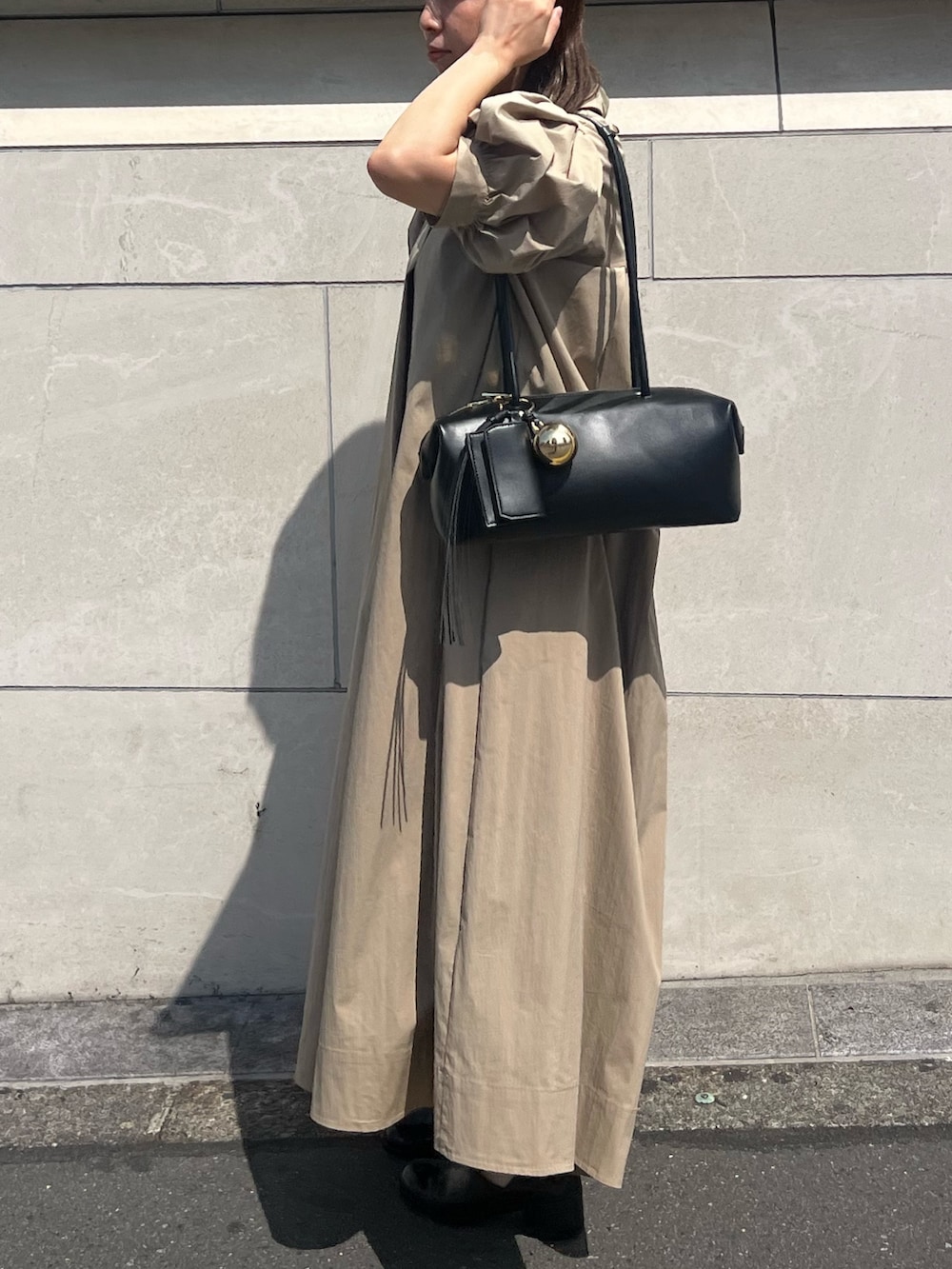 ベージュ系のワンピース、ブラック系のボストンバッグ、ブラック系のパンプスを着用したレディースの夏コーディネートの3枚目の写真