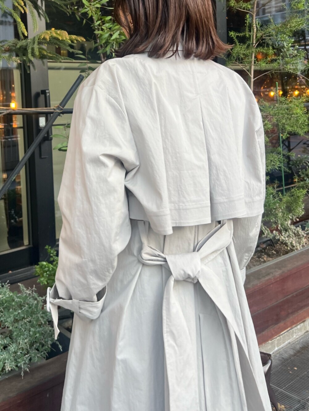 ブラック系のブーツ、グレー系のトレンチコート、ブラウン系のハンドバッグを着用したレディースの冬コーディネートの5枚目の写真