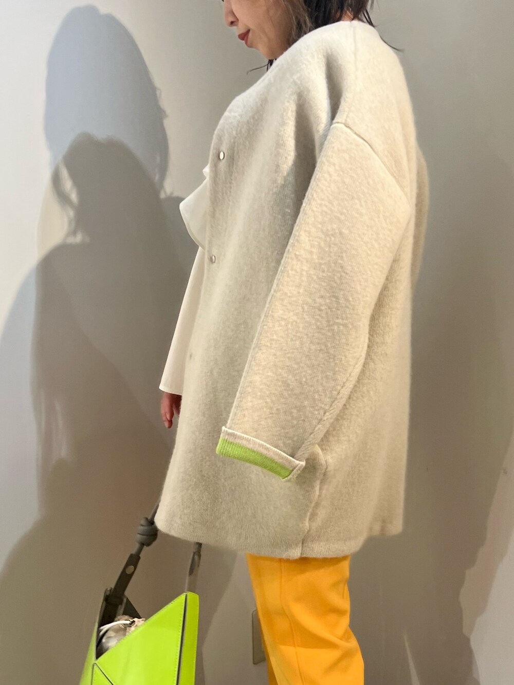 ホワイト系のシャツ/ブラウス、ホワイト系のカーディガン/ボレロ、イエロー系のハンドバッグを着用したレディースの冬コーディネートの4枚目の写真