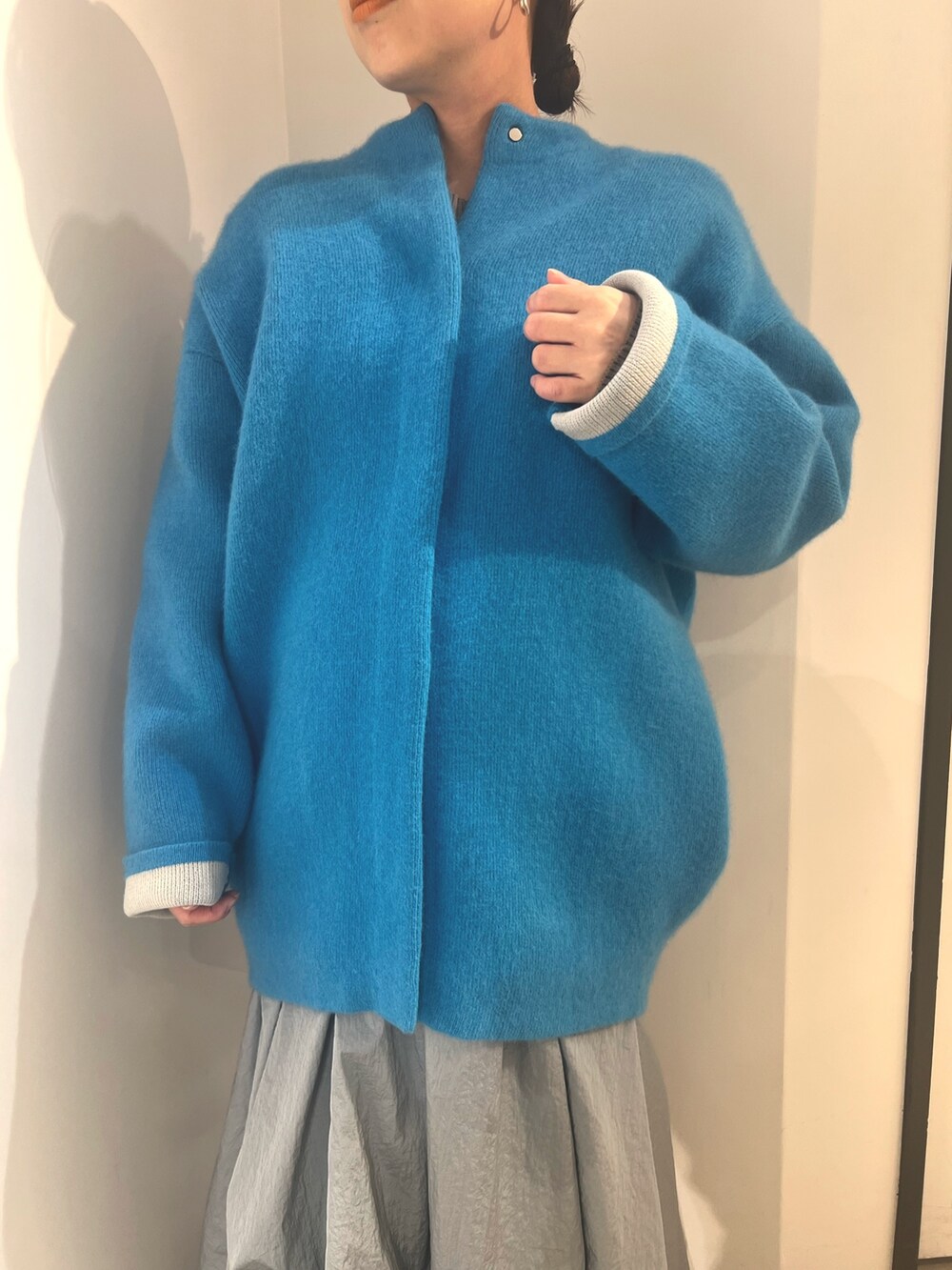 ブルー系のノーカラージャケット、ブルー系のスカート、ホワイト系のブーツを着用したレディースの夏コーディネートの4枚目の写真