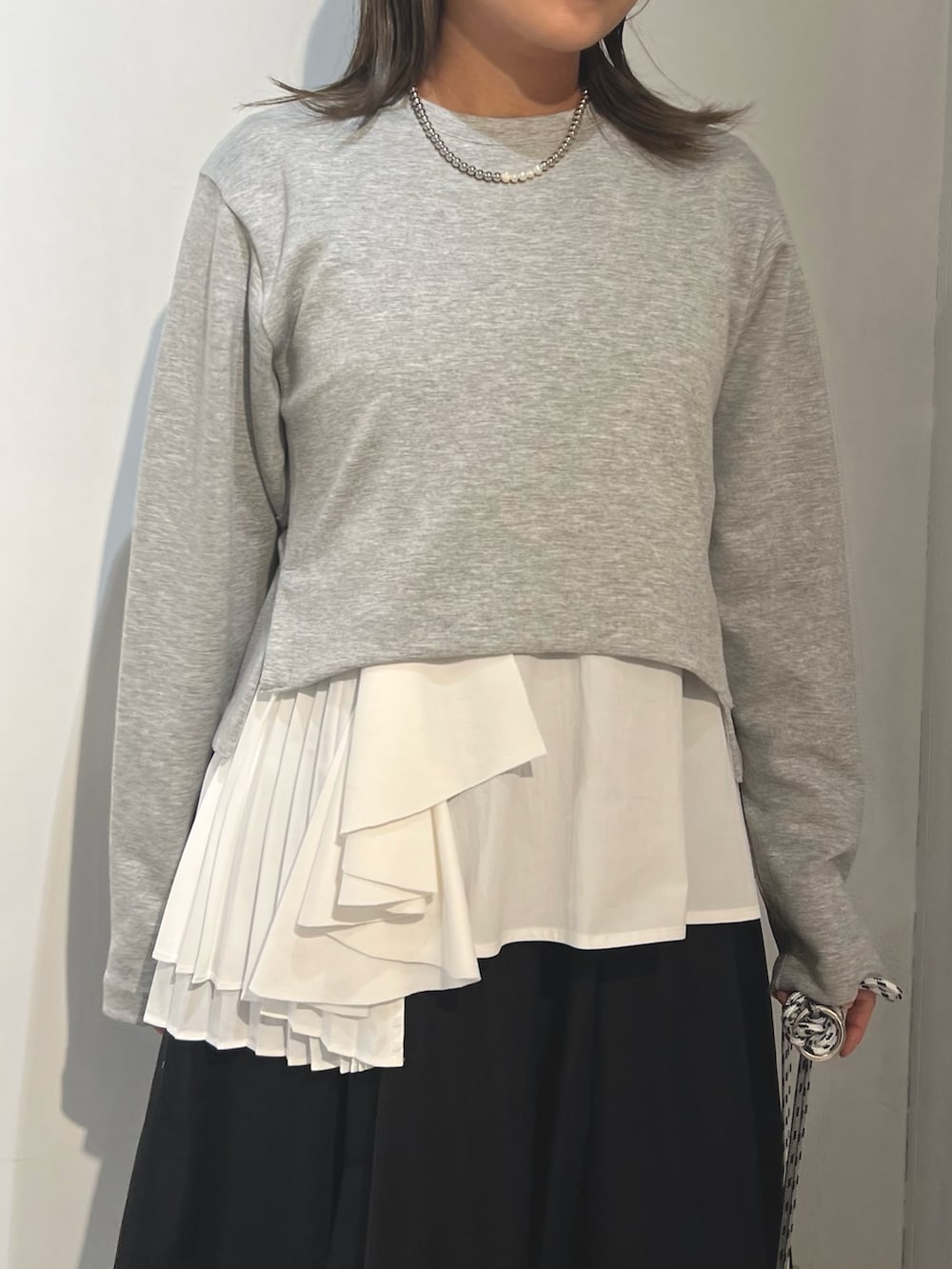 グレー系のTシャツ/カットソー、ブラック系のスカート、ブルー系のスニーカーを着用したレディースの冬コーディネートの5枚目の写真