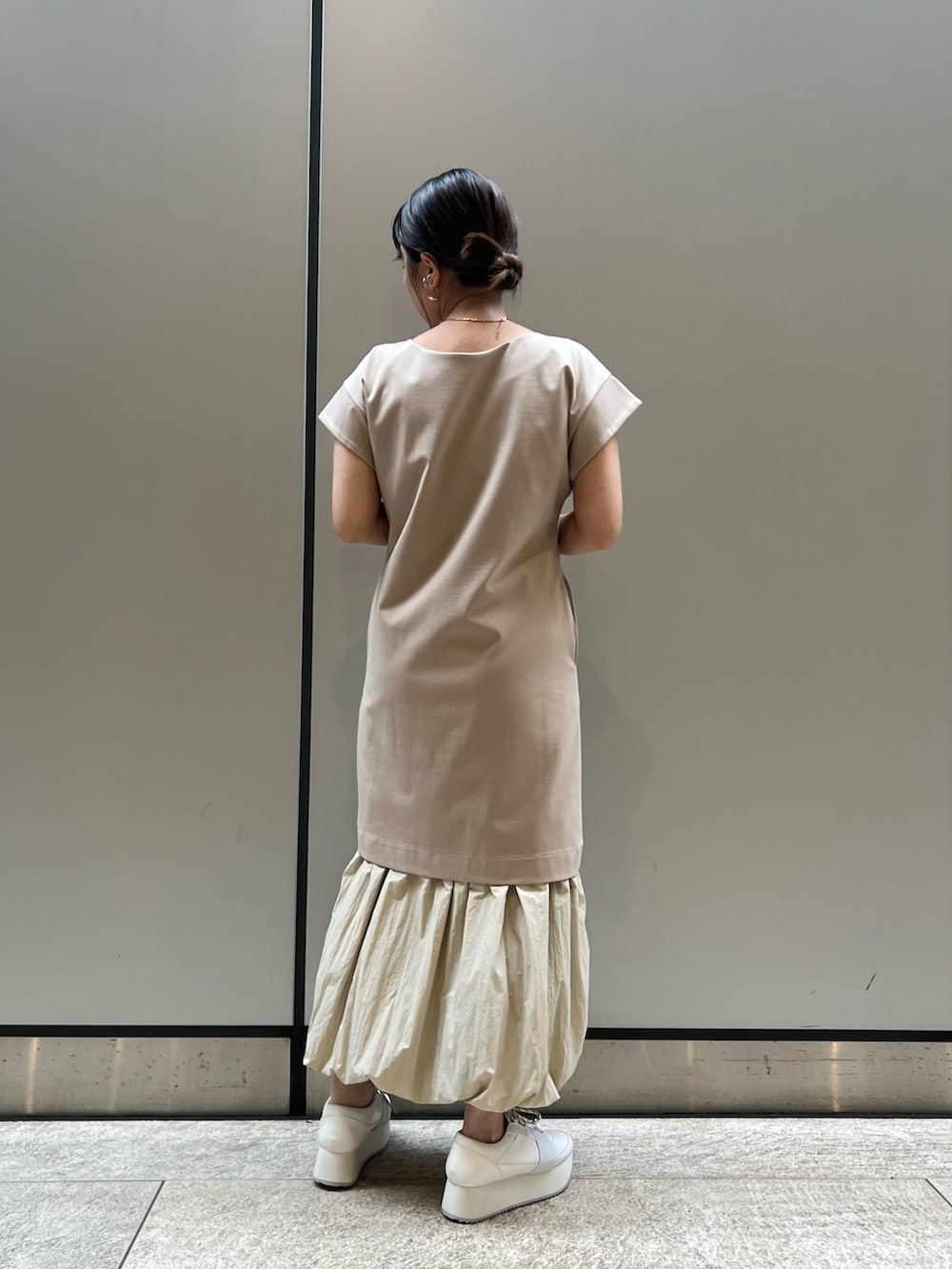 ベージュ系のワンピース、ホワイト系のスニーカー、ブラウン系のブルゾンを着用したレディースの春コーディネートの6枚目の写真