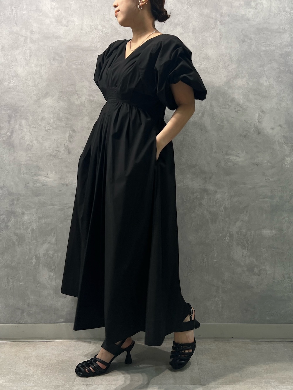 ブラック系のワンピース、ブラック系のサンダル、シルバー系のネックレスを着用したレディースの春コーディネートの2枚目の写真