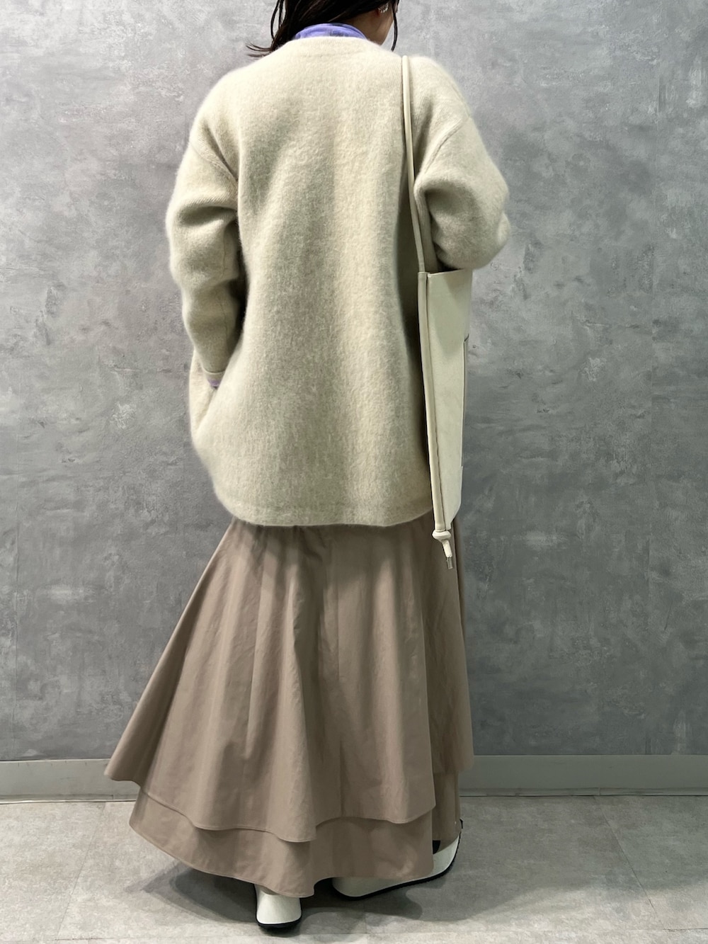 ホワイト系のノーカラージャケット、パープル系のニット/セーター、ベージュ系のスカートを着用したレディースの夏コーディネートの3枚目の写真