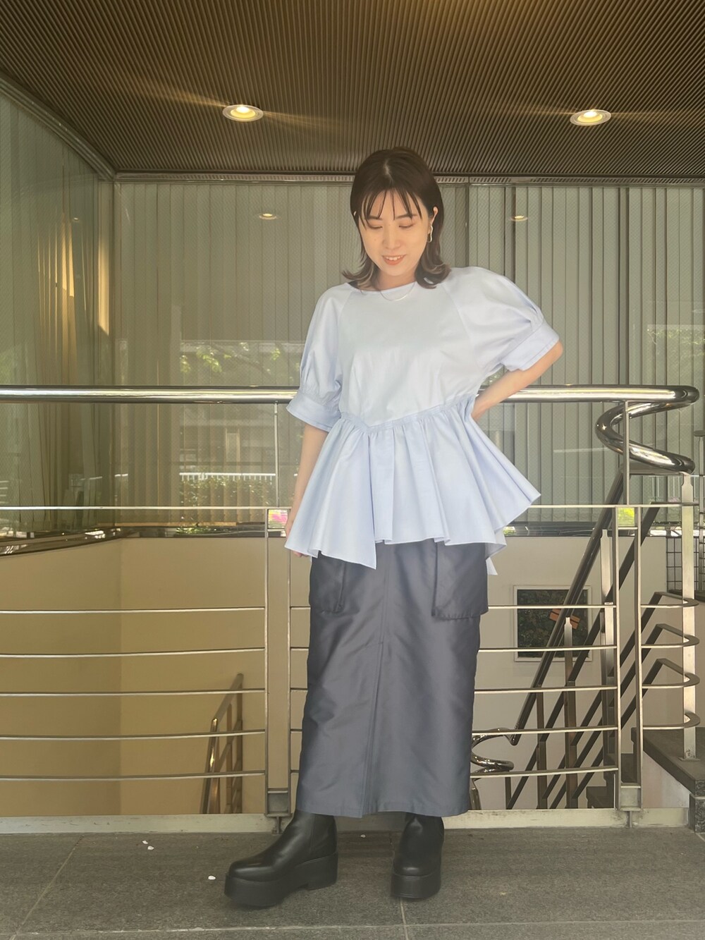 ブルー系のシャツ/ブラウス、ブルー系のスカート、ブラック系のブーツを着用したレディースの春コーディネートの2枚目の写真