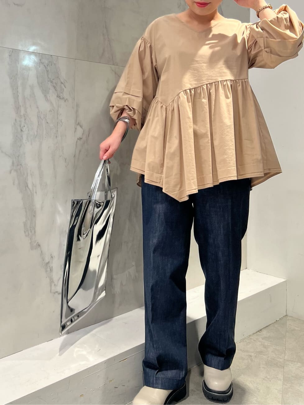 ベージュ系のシャツ/ブラウス、シルバー系のトートバッグ、ブルー系のスラックスを着用したレディースの冬コーディネートの2枚目の写真