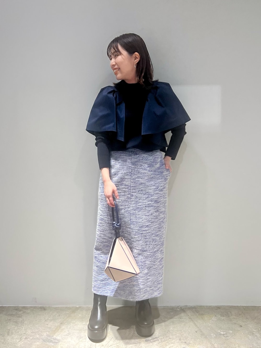 ブラック系のブーツ、ブルー系のニット/セーター、ブルー系のスカートを着用したレディースの春コーディネートの6枚目の写真