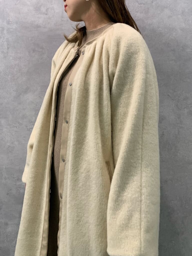 ベージュ系のワンピース、ホワイト系のハンドバッグ、ベージュ系のノーカラーコートを着用したレディースの秋コーディネートの4枚目の写真