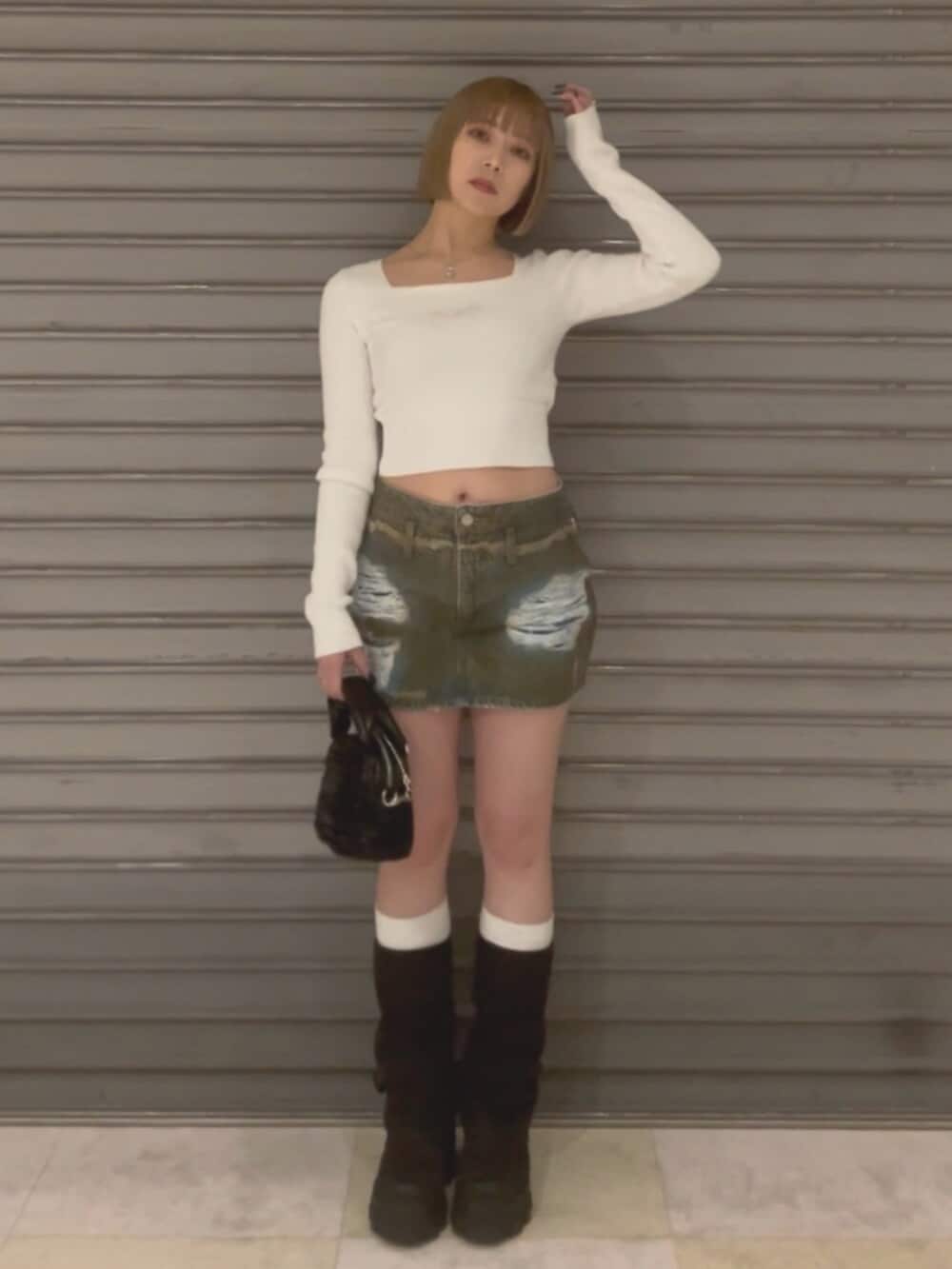 ブラウン系のブルゾン、ホワイト系のニット/セーター、ブラウン系のスカートを着用したレディースの冬コーディネートの2枚目の写真