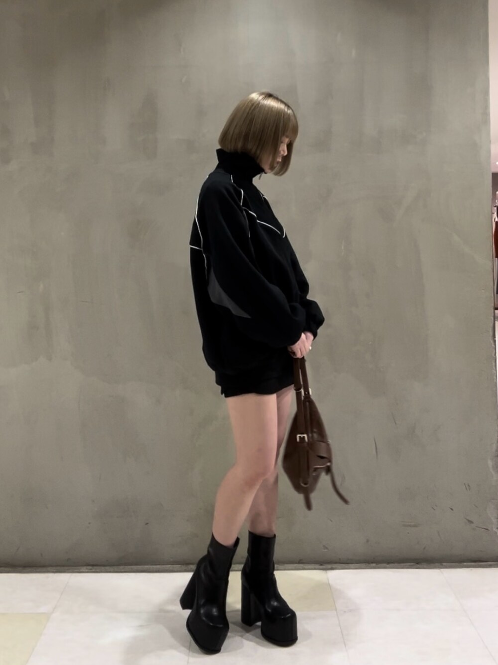 ブラック系のTシャツ/カットソー、ブラック系のスカート、ブラウン系のハンドバッグを着用したレディースの冬コーディネートの4枚目の写真