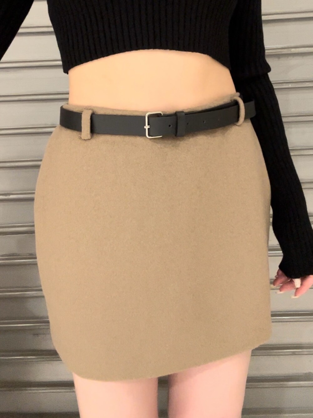 ホワイト系のダウンベスト、ブラック系のニット/セーター、ベージュ系のスカートを着用したレディースの秋コーディネートの9枚目の写真