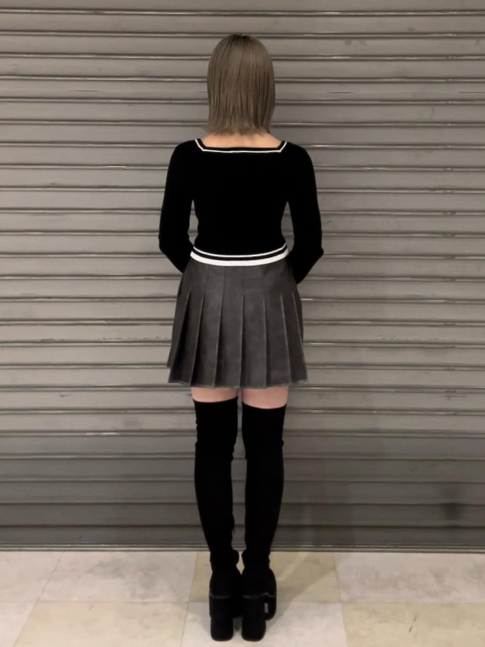 グレー系のブルゾン、グレー系のスカート、ブラック系のニット/セーターを着用したレディースの秋コーディネートの6枚目の写真