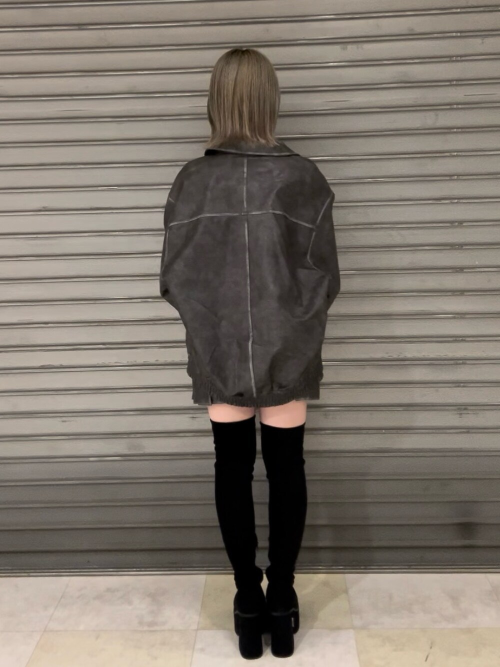 グレー系のブルゾン、グレー系のスカート、ブラック系のニット/セーターを着用したレディースの秋コーディネートの5枚目の写真