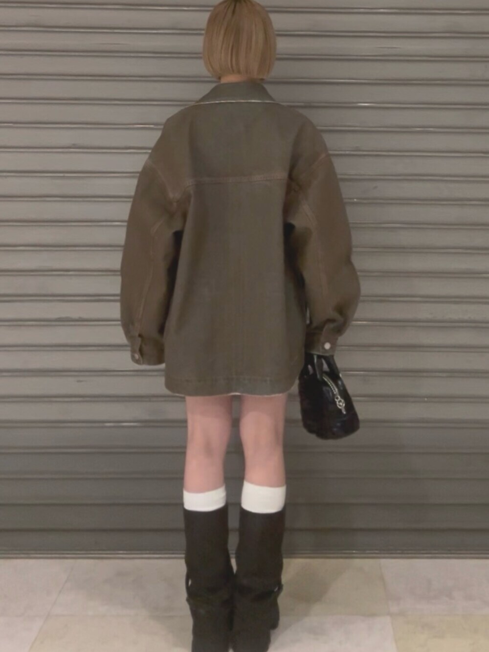 ブラウン系のブルゾン、ホワイト系のニット/セーター、ブラウン系のスカートを着用したレディースの冬コーディネートの5枚目の写真