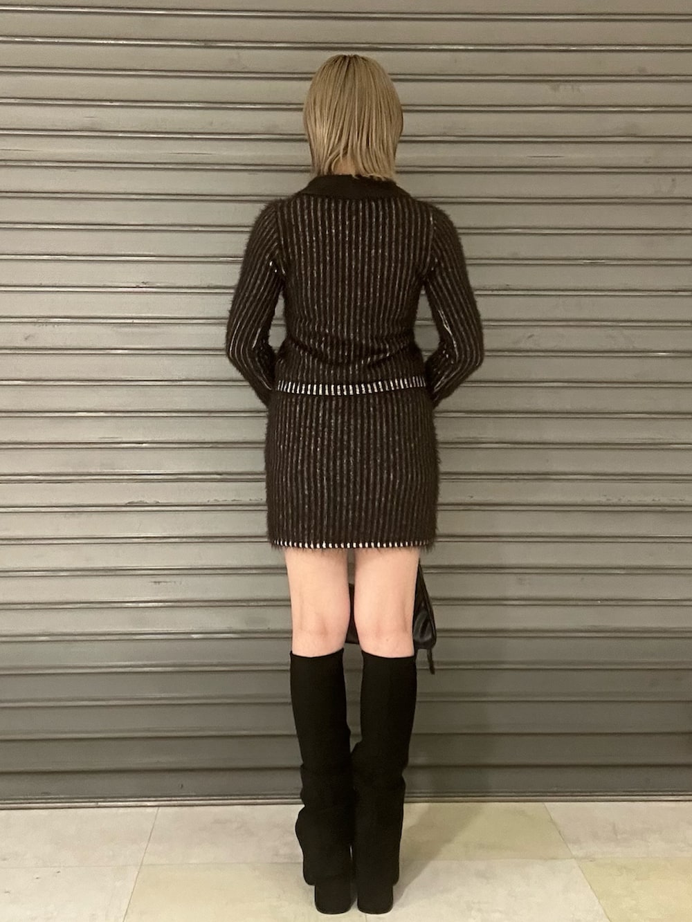 ブラウン系のニット/セーター、ブラウン系のスカート、ブラック系のブーツを着用したレディースの秋コーディネートの3枚目の写真