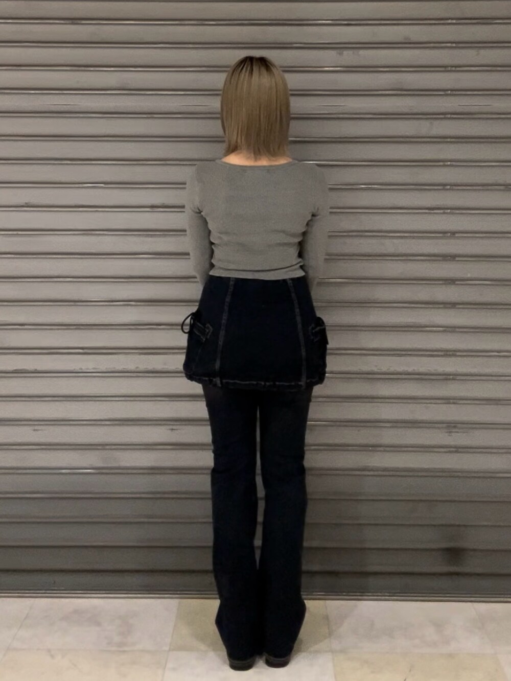 ブルー系のデニムパンツ、グレー系のニット/セーター、ブラック系のブーツを着用したレディースの秋コーディネートの5枚目の写真