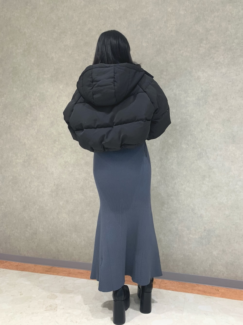 ブルー系のワンピース、ブラック系のダウンジャケット/コート、ブラック系のブーツを着用したレディースの冬コーディネートの3枚目の写真